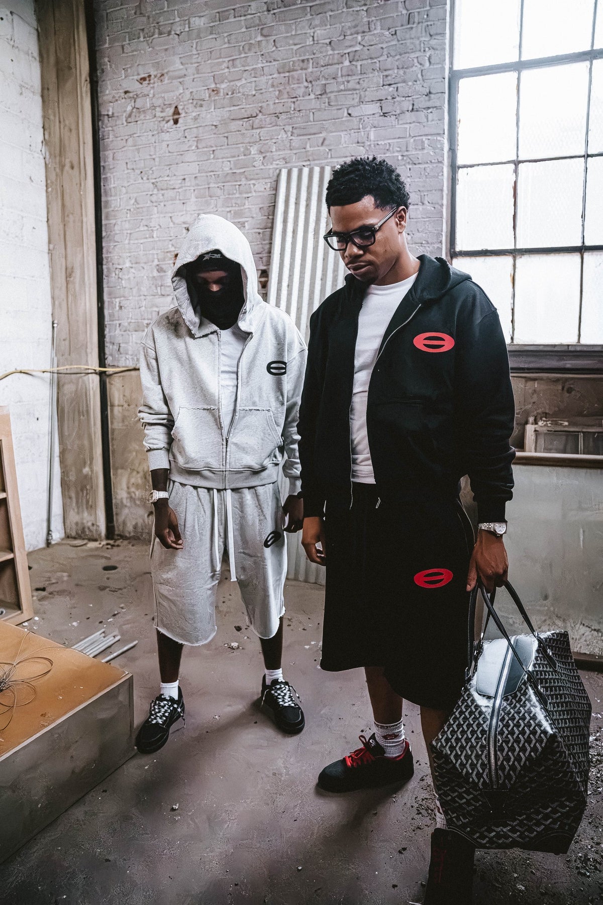 Two men wearing SOVRCLUB sets with a duffle bag